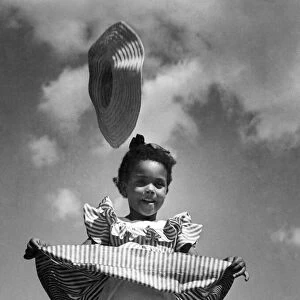 Little child wearing candy stripped dress is caught by the wind