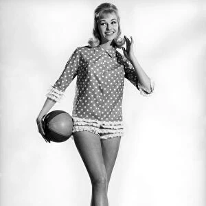 Model Jo Waring wearing a polka dot patterned top and holding a beach ball