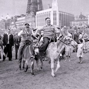 The old folks go young for a day. Two men racing donkeys on Blackpool beach. 1959
