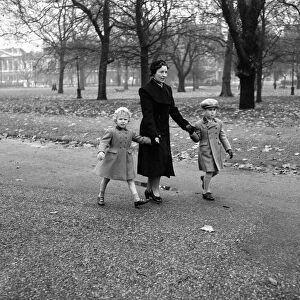 Princess Anne (4) and Prince Charles (6) walk through Green Park with their Governess