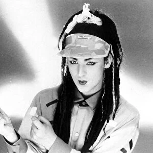Singer Boy George with hair extensions wearing a cap with his name on it