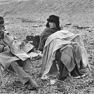 Vanessa Redgrave and James Fox sit in their cast chairs on the pebbled beach at Dover