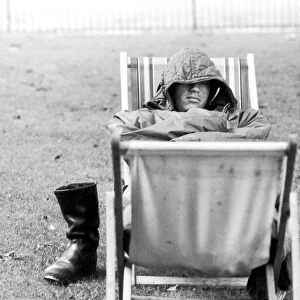 A weary traveller removes his boots as he takes a rest on a bed made from two deckchairs