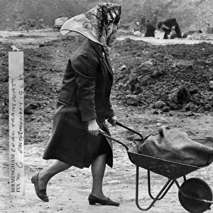Woman wheeling a wheelbarrow filled with a sack of coal at Bentley Lane in Walsall