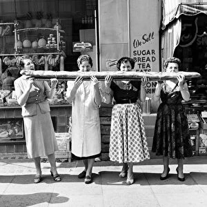 Four women sharing a 9 foot long baguette in Soho, London. Circa 1955