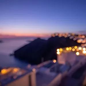 World environment day concept: Bokeh light and blur of sunset twilight town on Santorini, Greece. Sea view and island landscape, abstract cityscape