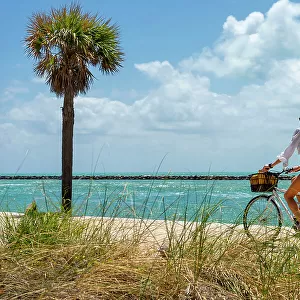 Florida, Miami Beach, South Pointe Park, Woman biking on the beach