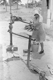 PUMPING WATER, 1940. A woman pumping water in Pie Town, New Mexico PUMPING WATER, 1940. A woman pumping water in Pie Town, New Mexico