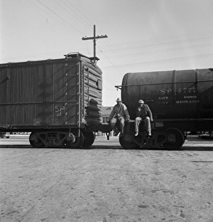 RAILROAD, 1937. Itinerant men riding outside a train hauling oil tanks in Kingsbury, California RAILROAD, 1937. Itinerant men riding outside a train hauling oil tanks in Kingsbury, California