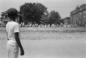 A young African American boy watching a group of people marching to protest the admission A young African American boy watching a group of people marching to protest the admission